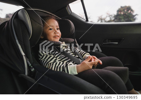 happy toddler girl sitting in car seat, safety baby chair travelling 130349695