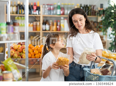 Child girl with mother choose consider cornflakes and oat flakes 130349824