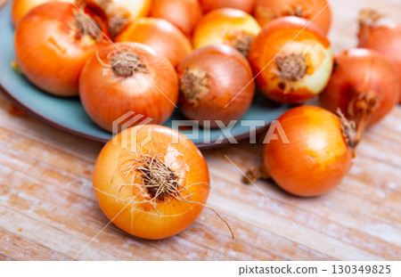 Yellow onion on kitchen table, food preparation 130349825