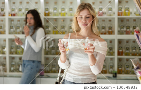Young woman choosing perfume in store Young woman choosing perfume in store 130349932