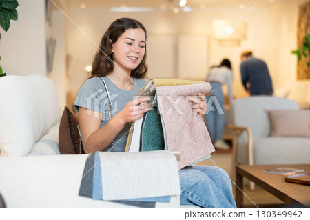 Portrait of woman choosing upholstery fabric in furniture salon Portrait of woman choosing upholstery fabric in furniture salon 130349942