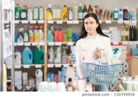 Woman with a full basket of goods and household chemicals in a supermarket 130349956