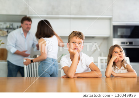 Brother and sister sit at table during quarrel between parents 130349959