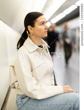 Girl is sitting on metro platform station, waiting for transport to arrive 130349960