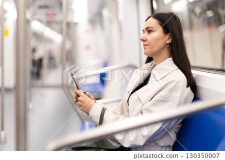 Woman in metro carriage points phone camera at an information board 130350007