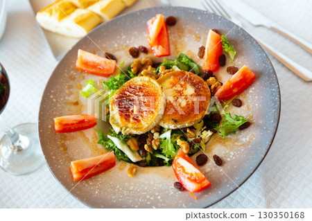 Appetizing salad with goat cheese, tomatoes and walnuts on plate 130350168