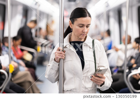 Woman using smartphone while traveling in subway car Woman using smartphone while traveling in subway car 130350199