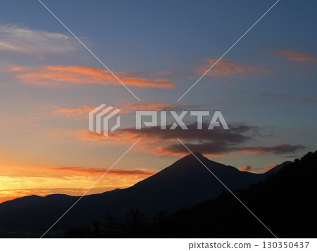 夏日的黃昏,磐梯山的輪廓上方,被夕陽染成紅色的雲彩在天空中閃耀,景色十分美麗,令人印象深刻。 夏日的黃昏,磐梯山的輪廓上方,被夕陽染成紅色的雲彩在天空中閃耀,景色十分美麗,令人印象深刻。 130350437