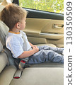 Child sitting in the back seat of a car, safely fastened with a seat belt and looking out the window 130350509