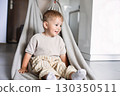 Happy child spending time at home while mother playfully pulls him on a blanket across the floor 130350511