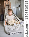 Happy child spending time at home while mother playfully pulls him on a blanket across the floor 130350515