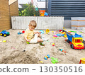 Child playing alone in a sandbox with toys on a playground, enjoying outdoor activities  130350516
