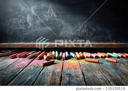 Colorful chalks on wooden floor with blackboard background Colorful chalks on wooden floor with blackboard background 130350519