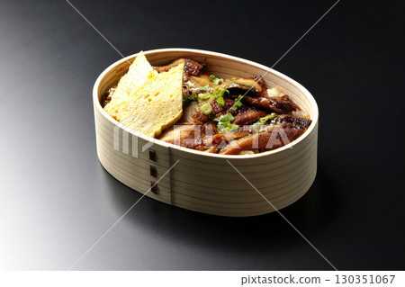 Eel bowl bento in a bento box photographed against a black background Eel bowl bento in a bento box photographed against a black background 130351067