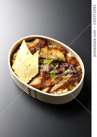 Eel bowl bento in a bento box photographed against a black background 130351091