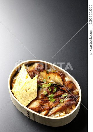 Eel bowl bento in a bento box photographed against a black background Eel bowl bento in a bento box photographed against a black background 130351092