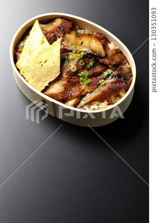 Eel bowl bento in a bento box photographed against a black background Eel bowl bento in a bento box photographed against a black background 130351093