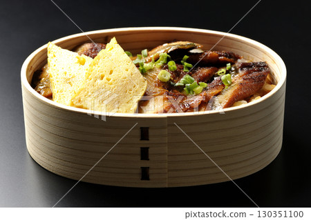 Eel bowl bento in a bento box photographed against a black background 130351100