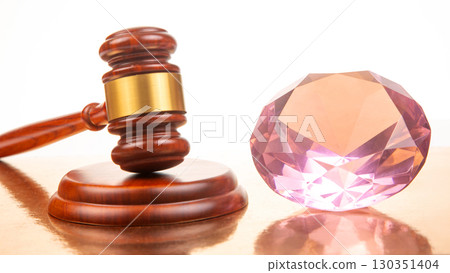 Gavel and pink gemstone showcased on a polished wooden surface in a soft-lit environment Gavel and pink gemstone showcased on a polished wooden surface in a soft-lit environment 130351404