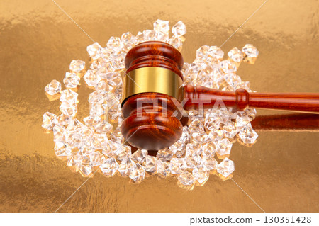 Legal gavel resting on a bed of sparkling crystal gems under a gold background Legal gavel resting on a bed of sparkling crystal gems under a gold background 130351428