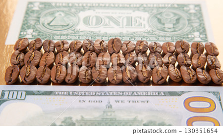 Coffee beans arranged in a line on top of a one hundred dollar bill and a one dollar bill Coffee beans arranged in a line on top of a one hundred dollar bill and a one dollar bill 130351654
