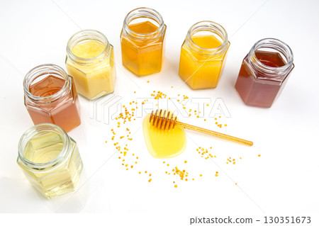 Variety of honey jars displayed with golden honey in the center on a white background Variety of honey jars displayed with golden honey in the center on a white background 130351673