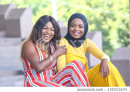 Two women sit close together, laughing and enjoying each other's company Two women sit close together, laughing and enjoying each other's company 130351674