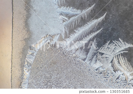 Intricate frost patterns forming on a cold window surface during winter mornings 130351685