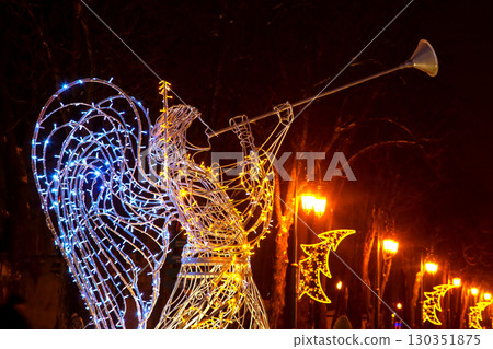 Holiday angel sculpture illuminated during evening celebration at city park pathway Holiday angel sculpture illuminated during evening celebration at city park pathway 130351875