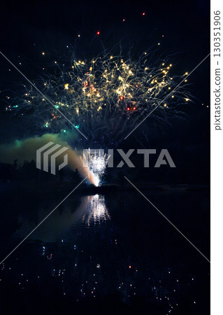 Colorful fireworks illuminate night sky over calm lake during summer celebration 130351906
