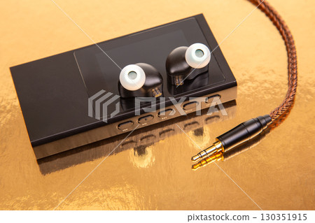 High-quality audio device with earphones on a reflective surface in a well-lit setting High-quality audio device with earphones on a reflective surface in a well-lit setting 130351915