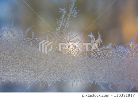 Frost patterns create intricate designs on a chilly window during a winter morning 130351917