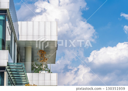 Modern buildings intertwined with blue sky and white clouds Modern buildings intertwined with blue sky and white clouds 130351939