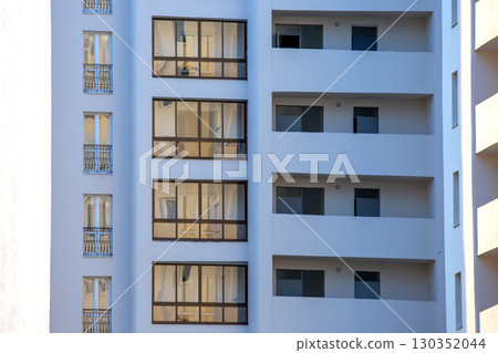 Modern apartment building with glass balconies in a sunny urban area Modern apartment building with glass balconies in a sunny urban area 130352044