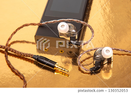 High-fidelity audio equipment with earphones and digital music player on golden surface 130352053