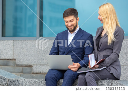 Business professionals collaborate outdoors in urban setting during daytime meeting 130352113
