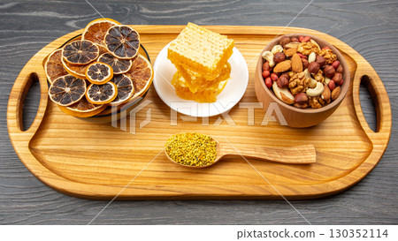 Dried fruit, honeycomb, and nuts displayed on a wooden tray in a cozy setting Dried fruit, honeycomb, and nuts displayed on a wooden tray in a cozy setting 130352114