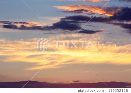 Colorful sunset sky over horizon filled with vibrant clouds during evening twilight hours 130352126