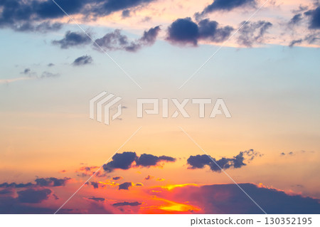 Beautiful sunset over a tranquil sky with vibrant clouds and warm colors near the horizon 130352195