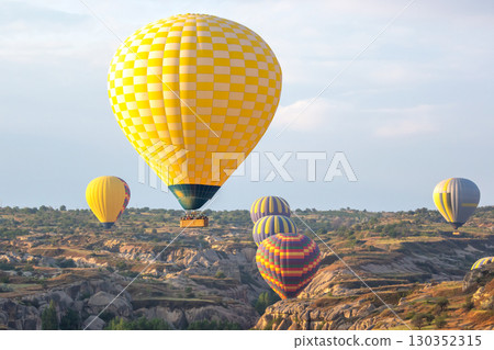 Colorful hot air balloons float over Cappadocia's unique landscape during sunrise in Turkey Colorful hot air balloons float over Cappadocia's unique landscape during sunrise in Turkey 130352315
