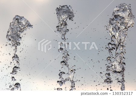 Captivating water jets create mesmerizing displays against a cloudy sky Captivating water jets create mesmerizing displays against a cloudy sky 130352317