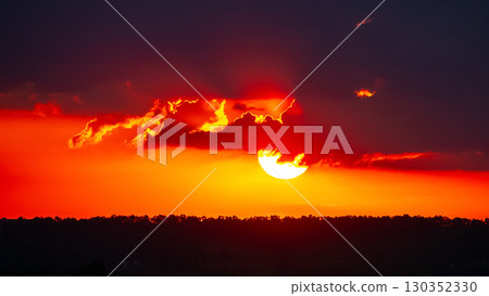 Stunning sunset paints the sky with vibrant hues over a distant horizon 130352330