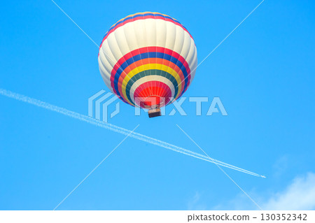 Colorful hot air balloon soaring high against a clear blue sky on a sunny day Colorful hot air balloon soaring high against a clear blue sky on a sunny day 130352342
