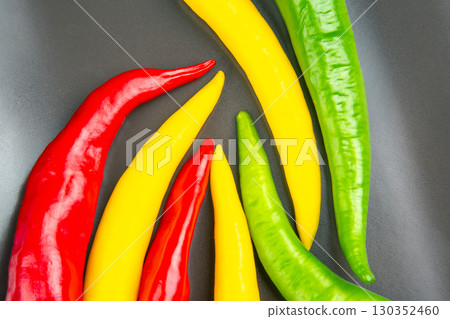 Colorful assortment of chili peppers arranged on a black surface in a vibrant display Colorful assortment of chili peppers arranged on a black surface in a vibrant display 130352460