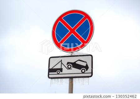 No parking sign with tow truck symbol and icicles in winter landscape 130352462