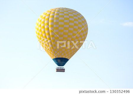 Colorful hot air balloon flying above a scenic landscape in clear blue sky 130352496