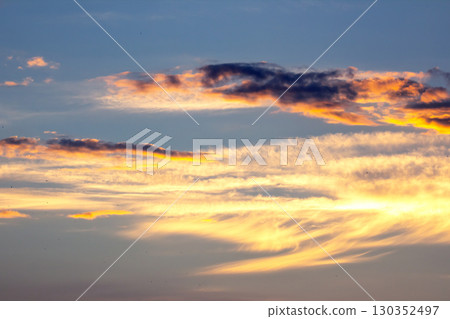 Vibrant sunset sky with colorful clouds over a tranquil landscape during evening hours 130352497