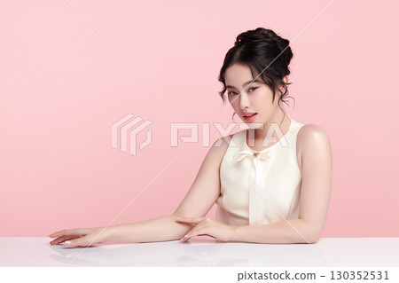 A beautiful young Asian woman with clean, fresh skin against a pink background. Skincare, facial treatment, cosmetology, beauty, and spa. An elegant portrait of an Asian woman. A beautiful young Asian woman with clean, fresh skin against a pink background. Skincare, facial treatment, cosmetology, beauty, and spa. An elegant portrait of an Asian woman. 130352531