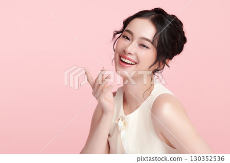 A beautiful young Asian woman with clean, fresh skin against a pink background. Skincare, facial treatment, cosmetology, beauty, and spa. An elegant portrait of an Asian woman. A beautiful young Asian woman with clean, fresh skin against a pink background. Skincare, facial treatment, cosmetology, beauty, and spa. An elegant portrait of an Asian woman. 130352536