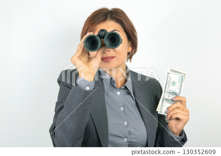 Businesswoman in professional attire with cash and binoculars, spotting opportunities Businesswoman in professional attire with cash and binoculars, spotting opportunities 130352609